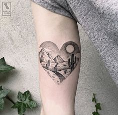 a heart shaped tattoo with mountains and cactus