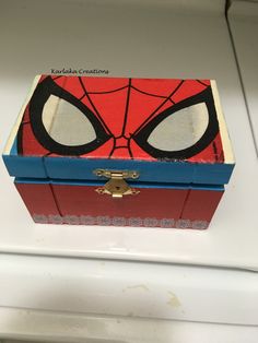 an open box with a spiderman face painted on the front and sides, sitting on top of a white surface