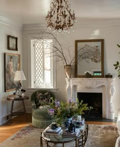 a living room filled with furniture and a chandelier hanging from the ceiling over a fire place