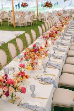 a long table is set with white linens and flowers