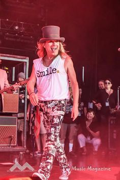 a man in a fedora is on stage with his mouth open and tongue out