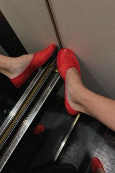 a woman's legs in red high heeled shoes on an escalator