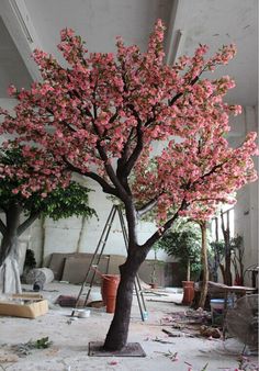 a tree with pink flowers is in the middle of a room that has been torn down