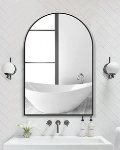 a white bathroom with a large oval mirror above the sink and an oval shaped mirror on the wall