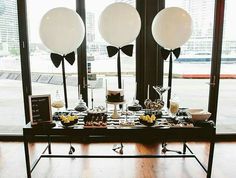 a table with plates and desserts on it in front of large windows at an event