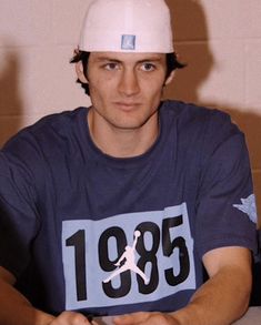 a man wearing a white hat sitting at a table with his hands on his hips