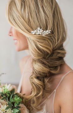 a woman wearing a wedding hair comb with flowers in her hair and holding a bridal bouquet