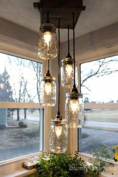 several mason jar lights hanging from the ceiling above a sink and faucet in front of a window