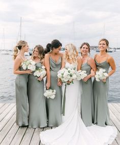 a group of women standing next to each other on a wooden dock near the water