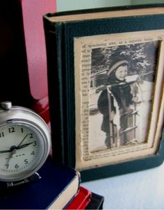 an alarm clock sitting on top of a table next to books and a framed photo