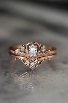 two wedding rings with diamonds on them sitting on a table together, one is gold and the other is white