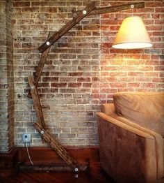 a lamp that is on in front of a brick wall with a tree branch as the base