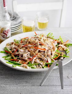 a white plate topped with meat and veggies next to two bottles of beer