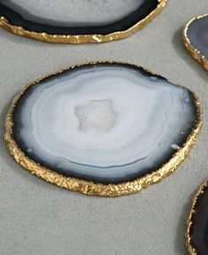 three gold and black agate coasters on a gray surface with white speckles