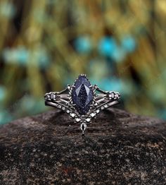 a close up view of a ring with a blue stone in the center on top of a rock