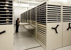 two people are standing in front of some type of storage unit that is filled with files