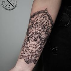 a woman's arm with an all seeing eye and lotus tattoo on the forearm