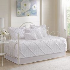 a white daybed in a bedroom next to a window with flowers on the bed