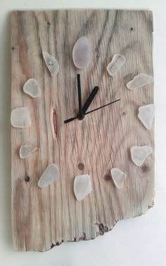 a clock made out of wood with white rocks on the face and numbers in black