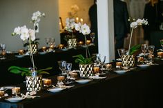 a long table is set up with candles and vases filled with white orchids