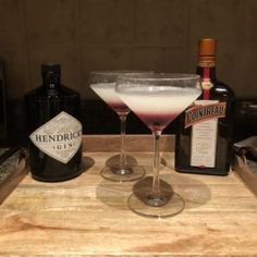 two martini glasses sitting on top of a wooden tray