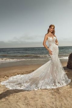 a woman standing on top of a beach next to the ocean wearing a wedding dress