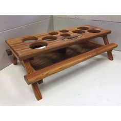 a wooden tray with four cups on it and two legs in the shape of a bench