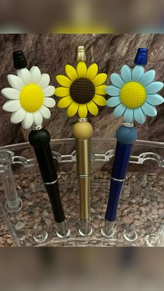 three pens and one flower are in a holder