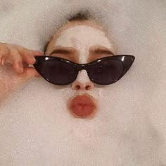 a woman wearing sunglasses in the bathtub with her nose covered by foamy bubbles