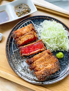 four pieces of food on a plate with chopsticks next to some rice and sauce