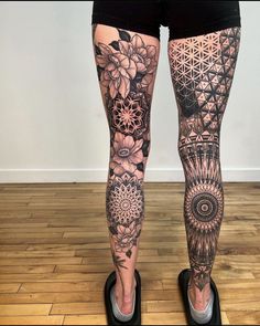 a woman's legs with tattoos on them and flowers in the middle of her leg