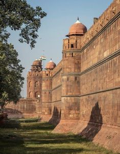 an old brick wall with two towers on each side and grass in the foreground