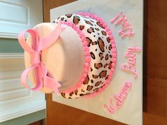 a leopard print cake with pink ribbon and name on the top, sitting on a table