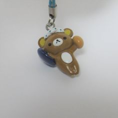 a brown teddy bear with a blue ribbon around it's neck on a white surface