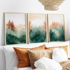 three paintings hanging on the wall above a bed with pillows and throw pillows in front of them