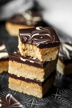 three pieces of cake sitting on top of a black plate with white and brown icing