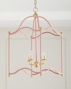 a pink and gold chandelier hanging from the ceiling in a room with white walls