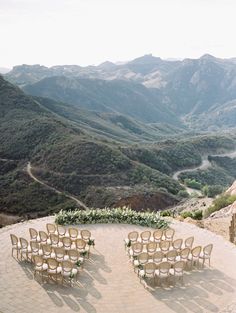 an outdoor ceremony set up with chairs and flowers on the ground in front of mountains