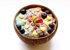 a wooden bowl filled with fruit on top of a white table