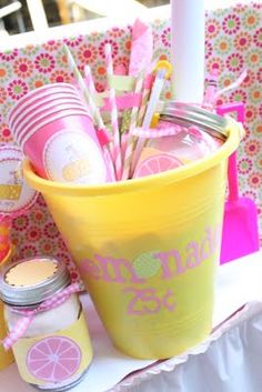 a yellow bucket filled with lots of pink and yellow items sitting on top of a table