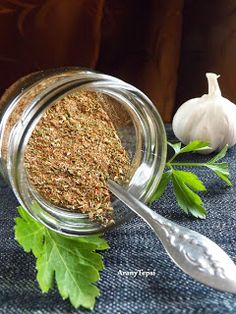 a glass jar filled with herbs next to a garlic and parsley