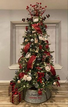 a christmas tree decorated with red and black plaid ribbon, ornaments and ribbons on it