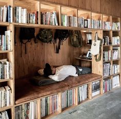 a person sleeping on a bench in front of bookshelves