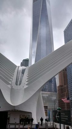 a large white sculpture in front of a tall building with a sky scraper on it's side