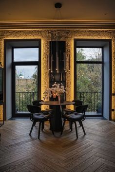 a dining room table with four chairs in front of two large windows that look out onto the outdoors