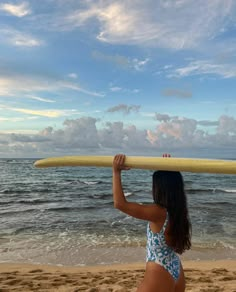 a woman holding a surfboard over her head on the beach