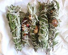 four bundles of herbs tied together on a white sheet with some other things in the background