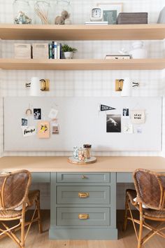 two wicker chairs sit in front of a desk with drawers and pictures on the wall