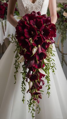 a bride holding a bouquet of red flowers