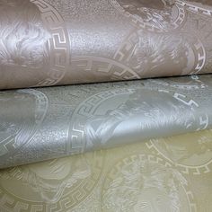 two rolls of metallic fabric on top of each other in different patterns and colors,